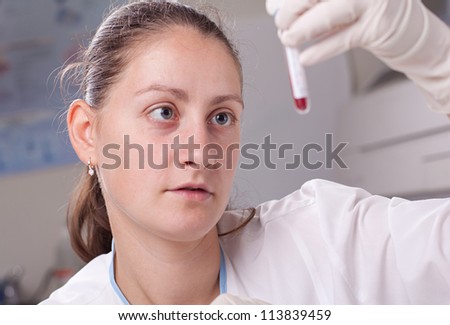 Woman holding test tube full of blood in laboratory environment
