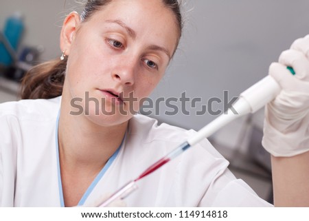 Woman taking sample from test tube with micro pipette