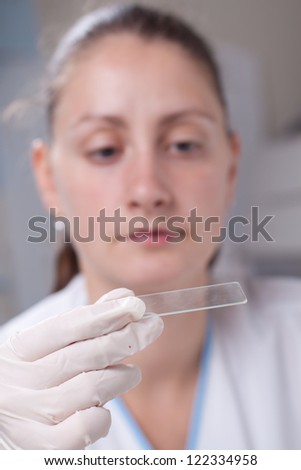 Woman dropping blood drop on sample glass with micro pipette