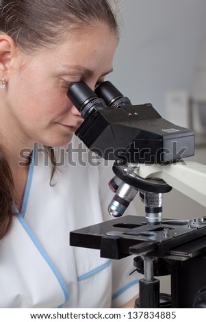 Young female doctor making research with microscope in laboratory.