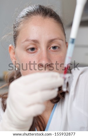 Woman dropping blood simple with micro pipette in test container