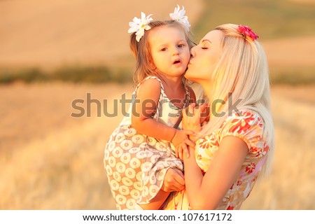happy mother and daughter kissing in a wheat field. outdoor shot