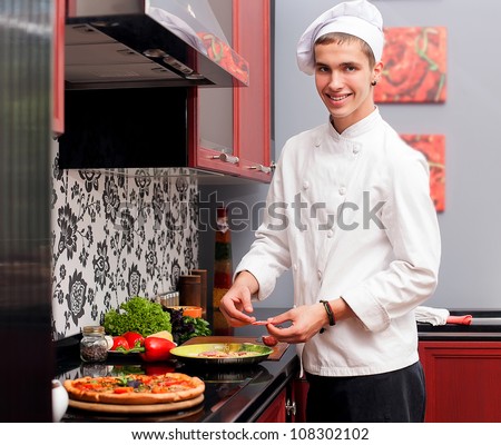 Portrait of confident male cook in modern restaurant kitchen smiling