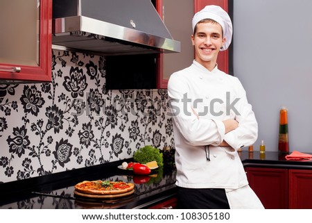 Portrait of confident male cook in modern restaurant kitchen smiling