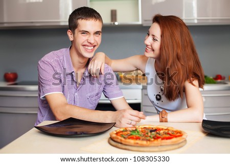 happy young couple have fun in modern  kitchen indoor while preparing fresh food
