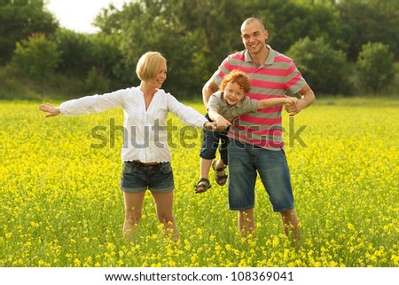 happy family having fun in the field with yellow flowers. Mother doing plane figure. outdoor shot