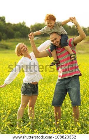 happy family having fun and doing plane figure in the field with yellow flowers. outdoor shot