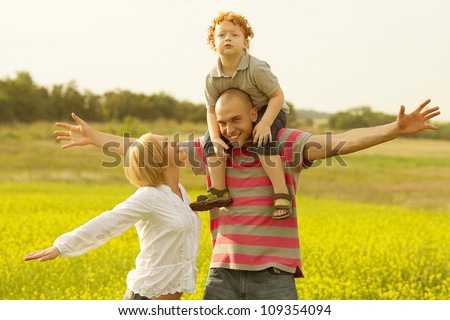 happy family having fun and doing plane figure in the field with yellow flowers. outdoor shot