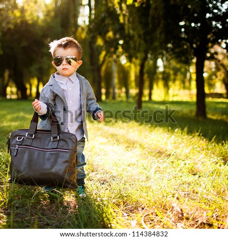 little boy in the suite with big bag in the park