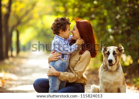 happy mother playing with her son in the park playing with the dog