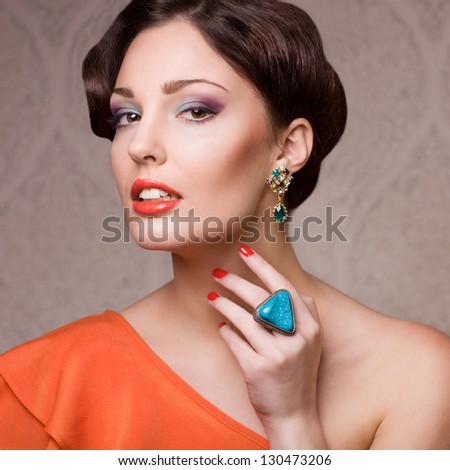 beautiful woman with hairstyle posing in studio with jewelry, close up portrait