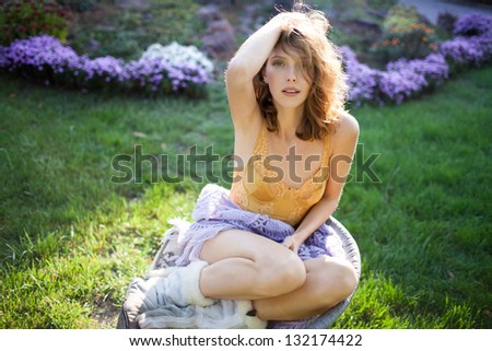 Fashion portrait of young sensual woman in garden  sitting in the chair