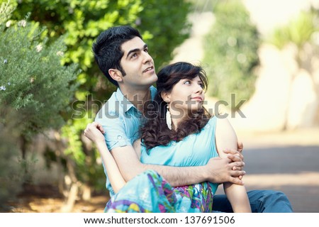 young couple in love sit in a park and looking into the distance