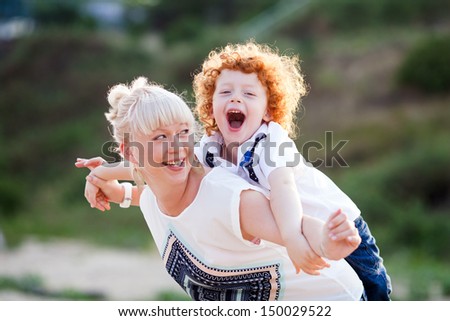 mum and son having fun outside, making plane figure and laughing