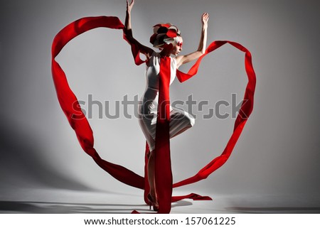 emotional portrait of fashion woman in exclusive dress posing in studio, making heart from textile in motion