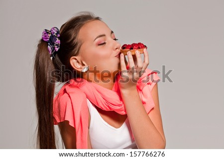 young cute girl eating cake in studio, close up