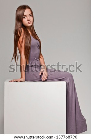 little cute girl sitting on cube in lond dress