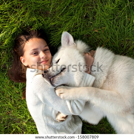 girl with her dog malamut laying on the grass , happy and smiling