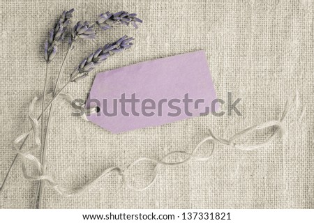 Dry lavender tied with a string and attached to a gift tag. Concept for memories, occasions, labels. On linen background. Top view. Post processed for more vintage and stylish look.