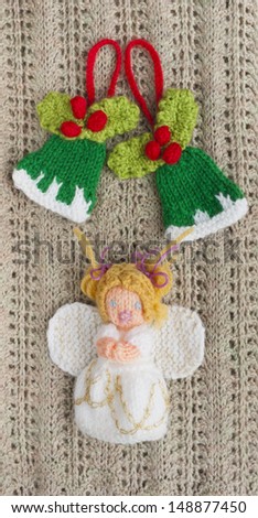 Christmas knitted praying angel under two knitted festive green bells decorated with red berries and mistletoe. Home made traditional Christmas tree decorations.