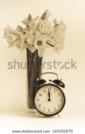 Vintage alarm clock with daffodil flowers. Concept for spring, dst or for getting old.