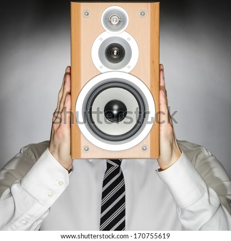 Man wearing a tie holding a speaker in front of his face