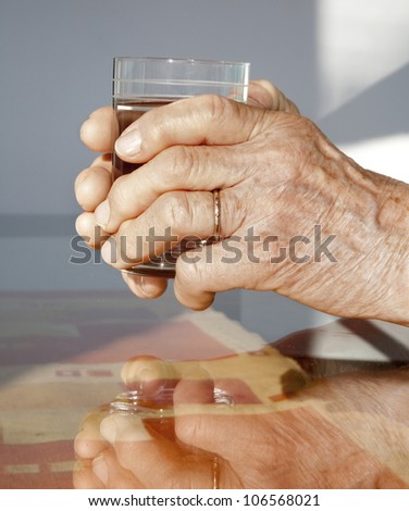 hands of old woman and glass of water