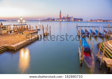 Venice - Boats and gondolas and San Giorgio Maggiore church in background in morning dusk.