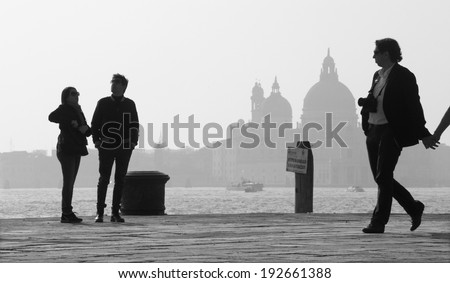 VENICE, ITALY - MARCH 14, 2014: Walking on the waterfront and silhouette of Santa Maria della Salute church.