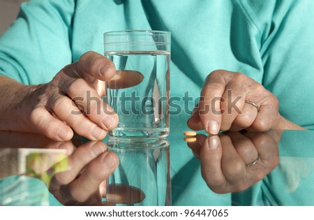 hands of old woman with a pill and water