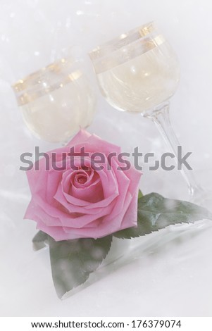 Rose flower and glasses with champagne with wet patches of light