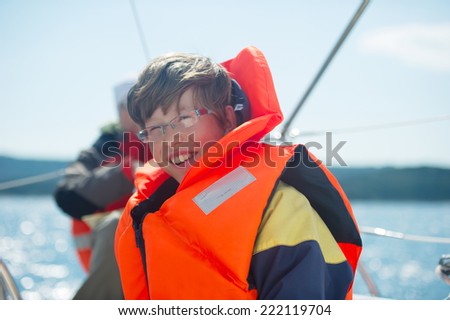 Teen smiling while wearing a life jacket with sea in the background.