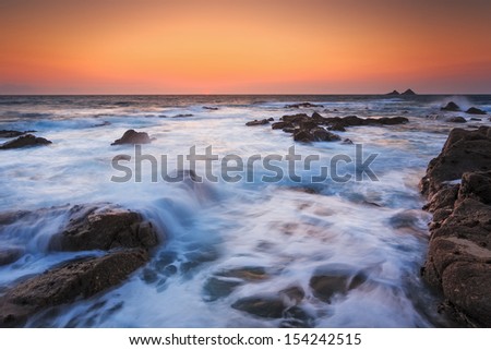 Sunset glow and waves on the coast of Cornwall at Nanjulian Cove Cornwall England UK