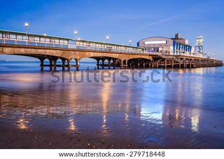 The lights of Bournemouth Pier at night reflected in the wet sand on the beach. Dorset  England UK Europe.