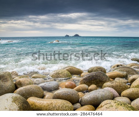 Boulder covered beach at Porth Nanven at the end of Cot Valley with the Brisons on the Horizon, Cornwall England UK Europe