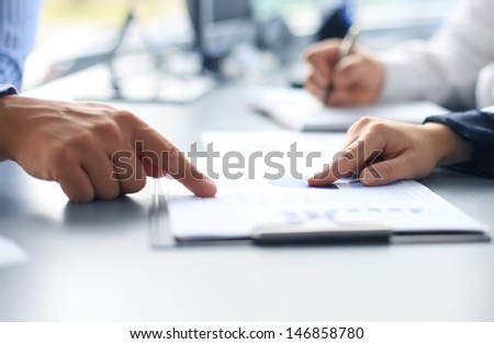 Unrecognizable Business Person Analyzing Graphs And Taking Notes