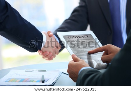 Image of human hands during discussion of paper and electronic documents at meeting