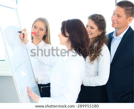 Young business team planning a new strategy standing grouped in front of a flip chart analyzing a chart