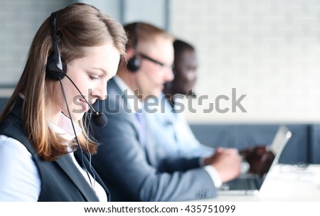Portrait of call center worker accompanied by her team. Smiling customer support operator at work