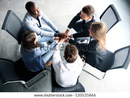 Creative business team putting hands together at the office
