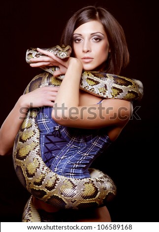 Sexy Brunette Holding Python Over Black Background Stock Photo