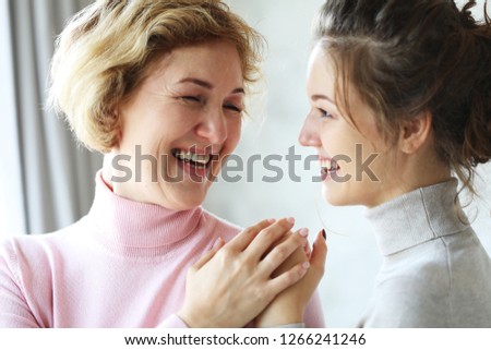 two charming adorable wonderful dreamy darling dear beautiful cheerful excited joyful mama and kind friendly attentive sensitive daughter holding hands looking at each other over grey wall, lifestyle