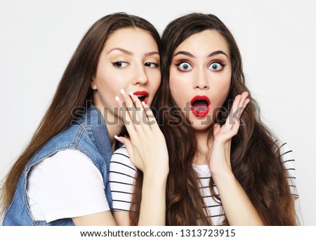 lifestyle, emotion and people concept: Portrait of two happy young women sharing secrets isolated over white  background