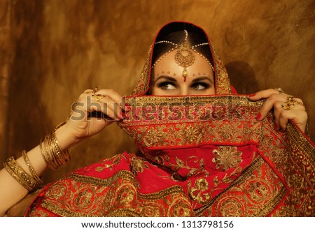 Portrait smiling of beautiful indian girl at home. Young woman model with golden jewelry set .