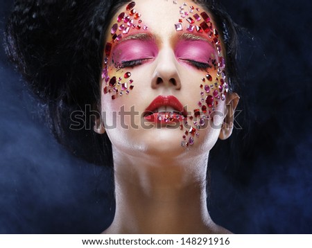 Closeup beauty portrait of attractive model face with bright rhinestones visage.Woman with eye closed.