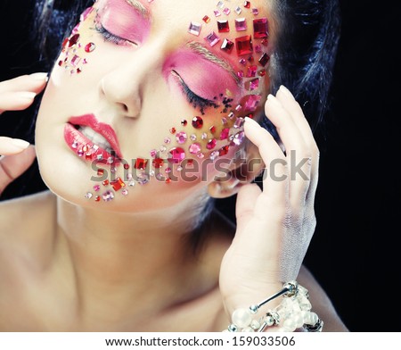 Closeup beauty portrait of attractive model face with bright rhinestones visage.Woman with eye closed.