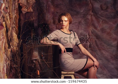 young fashion model sitting on a stool in drama decoration