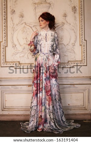 young beautiful woman in pink dress posing in luxury palace