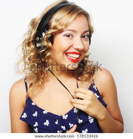 Young happy curly woman with headphones listening music