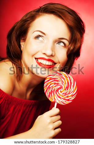 Portrait of young woman with lollipop on red background